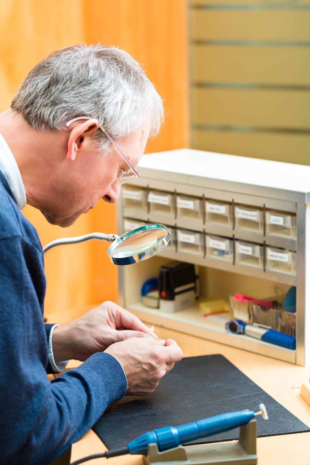 a hearing specialist repairing a set of hearing aids