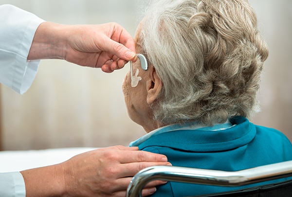 older patient with hearing loss having a hearing aid fitted to left ear