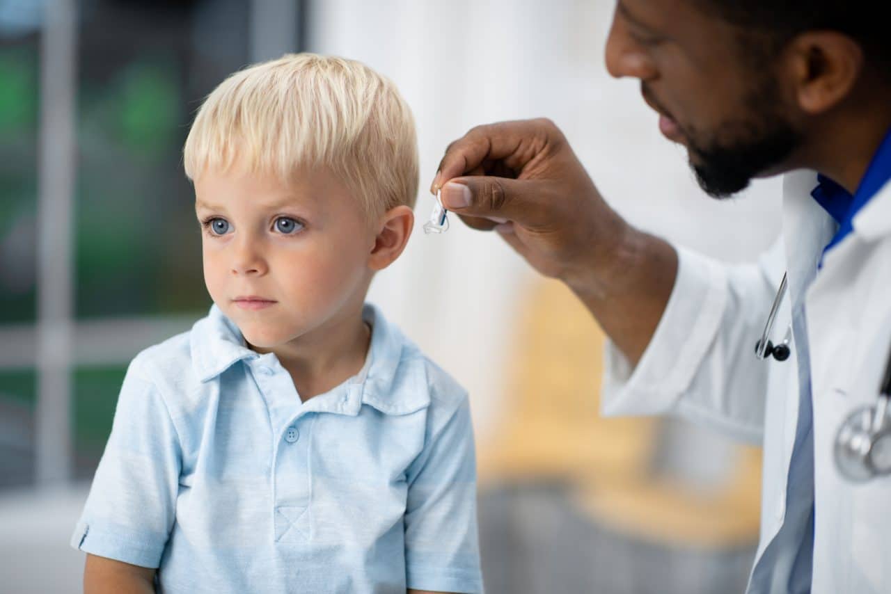 A boy being fitted with a hearing aid by his audiologist.