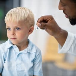 A boy being fitted with a hearing aid by his audiologist.