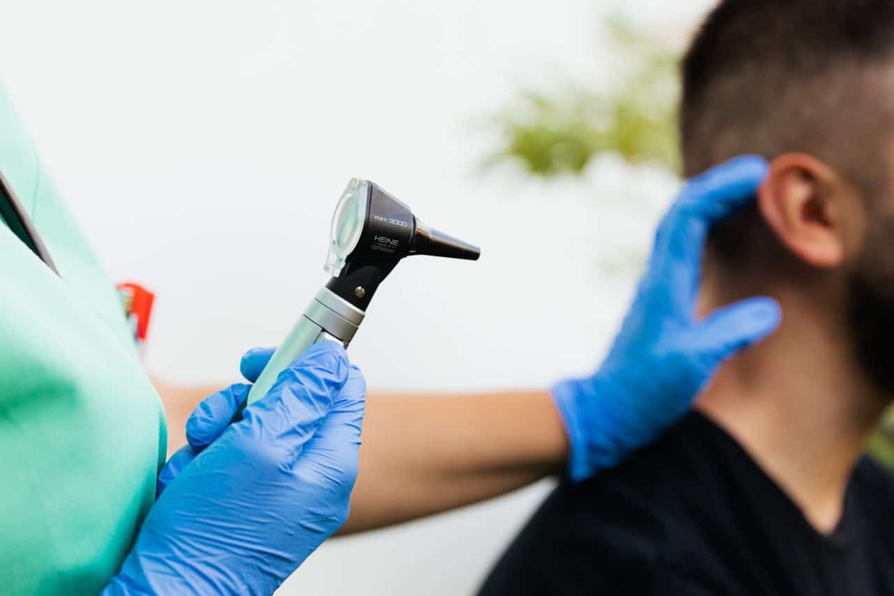 Doctor preparing to examine a man's ear for earwax buildup.