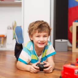 A boy playing with a remote-controlled car at home.