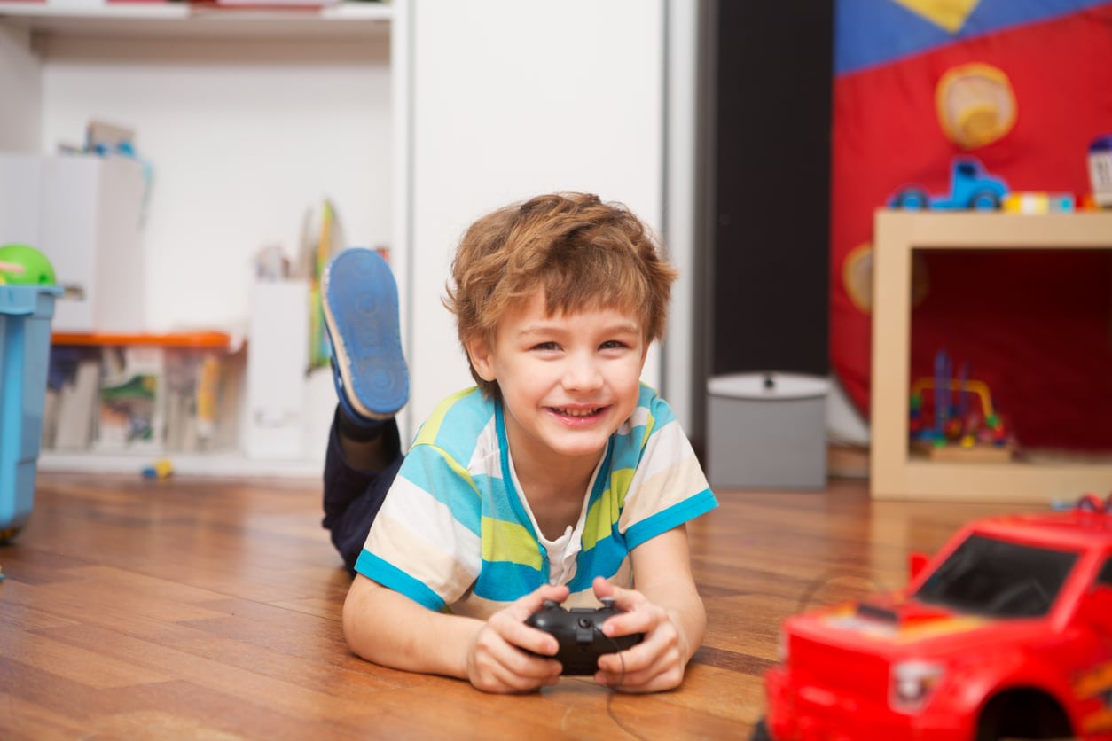 A boy playing with a remote-controlled car at home.