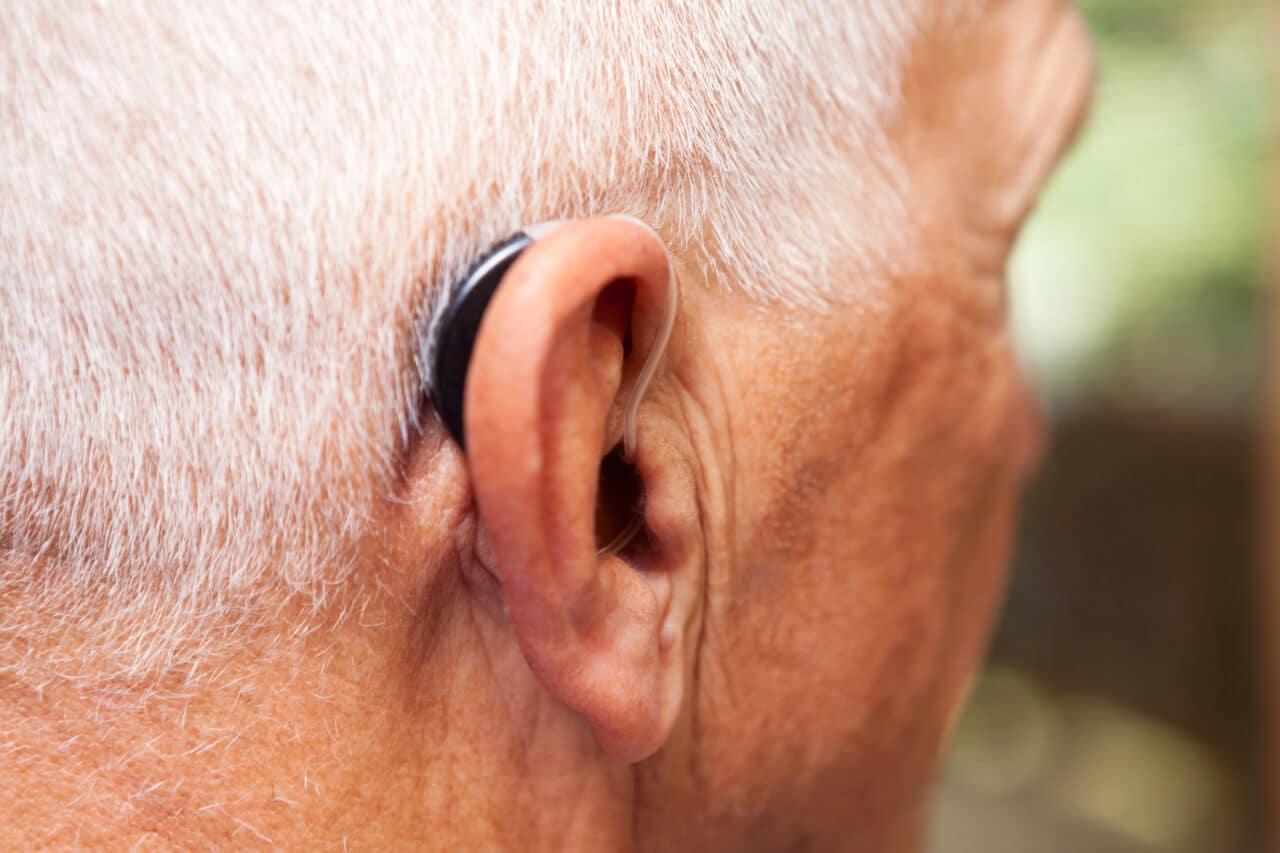 Close up of a senior man wearing a behind-the-ear hearing aid.