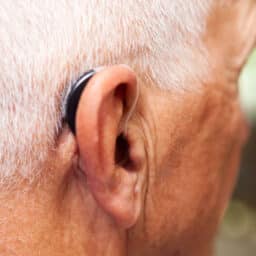 Close up of a senior man wearing a behind-the-ear hearing aid.