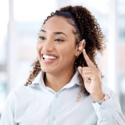 Happy woman pointing to her hearing aid