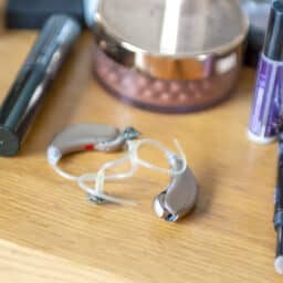 Hearing aids sitting on a table with makeup supplies.